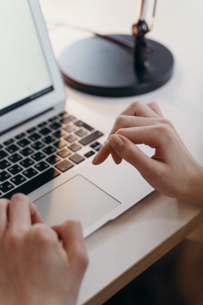 Close-up of hands using a laptops touchpad in an office environment, highlighting focus and technology.